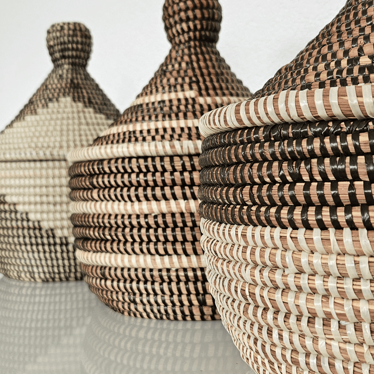 Image de trois paniers noirs et blancs rond avec couvercle tressés en fibres naturelles