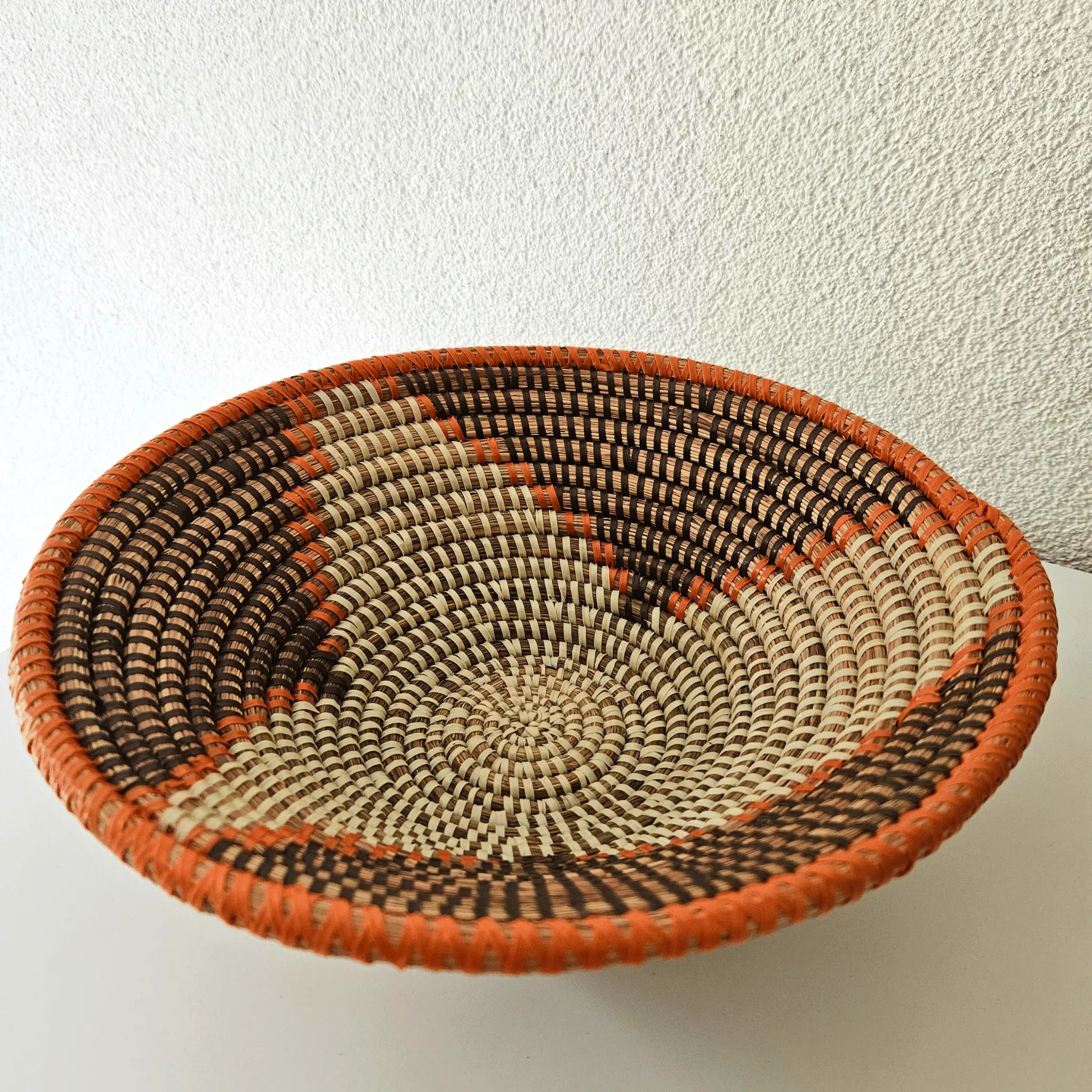 Image d'un panier à fruit orange, brun et beige tressé en fibres naturelles
