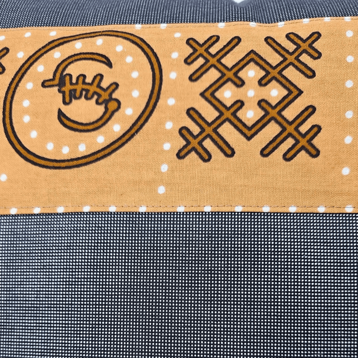 Image des détails d'un tissu en wax brun et tissu gris uni sur coussin