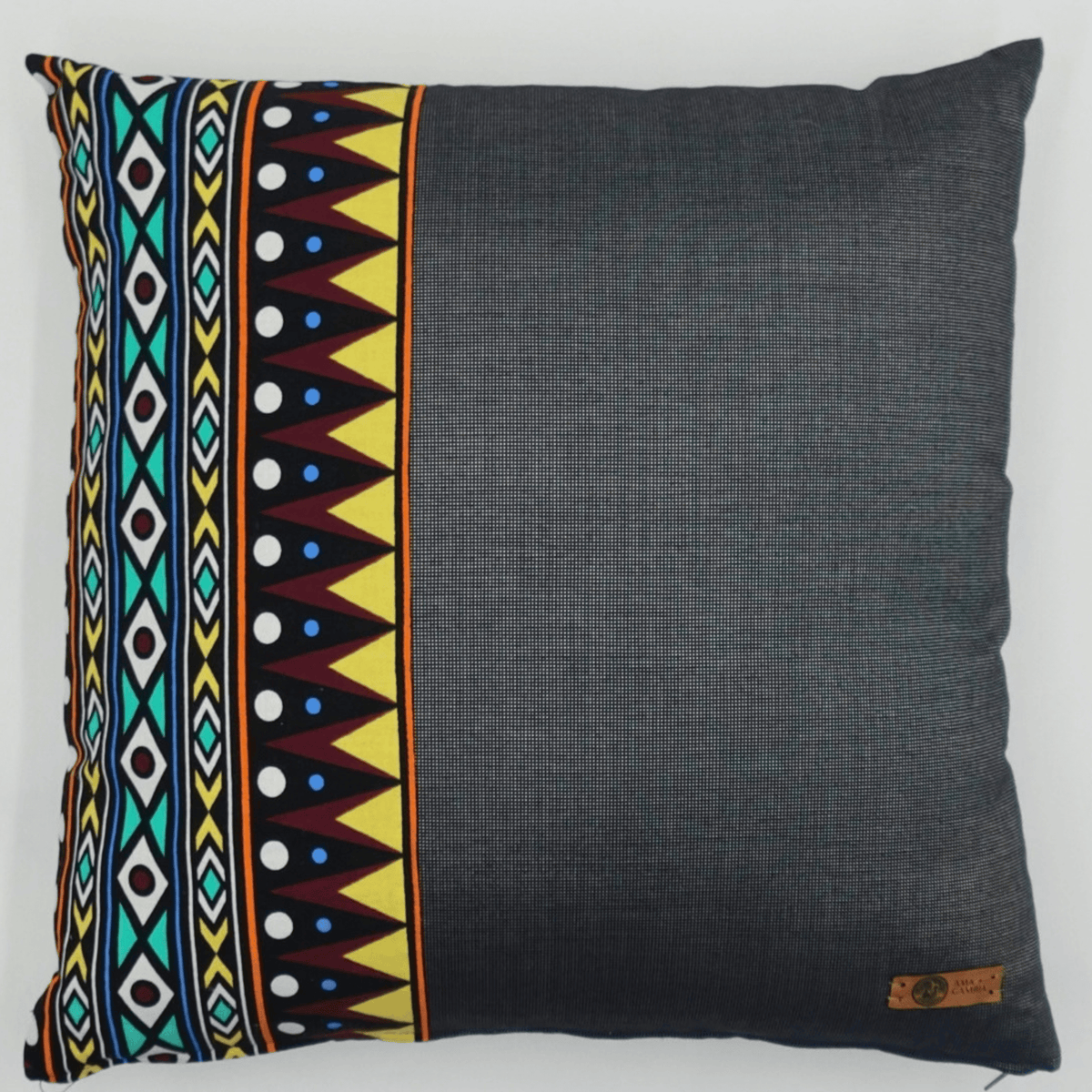 Image d'un coussin en wax motifs graphiques et tissu gris uni